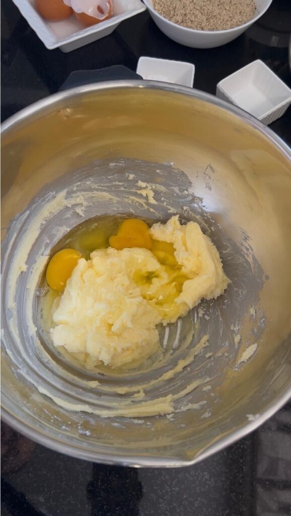 Beaten eggs mixed into creamed butter mixture, showing smooth and creamy texture for almond sablé cookie base