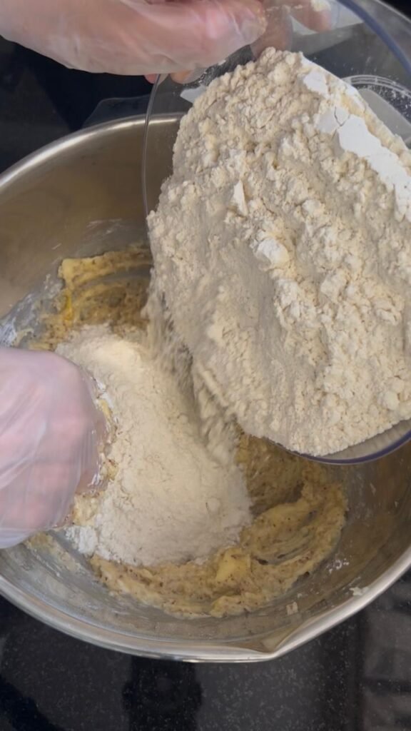 Ground almond flour and cornstarch being added to butter egg mixture for golden almond sablé cookies