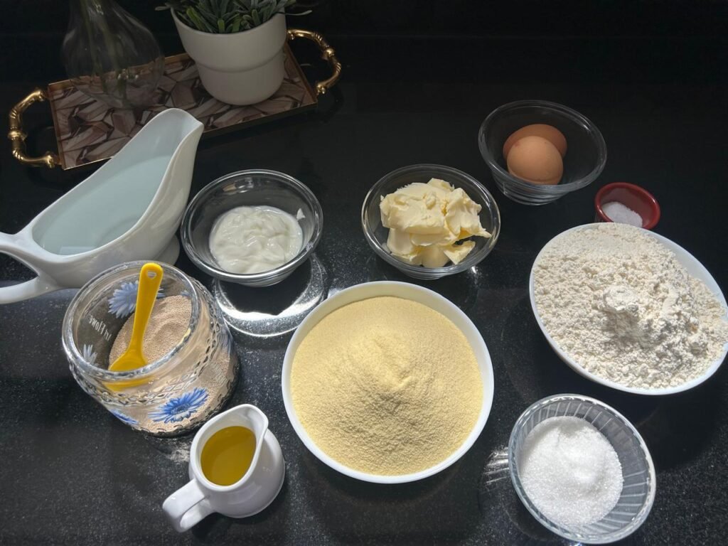 All ingredients for homemade crescent rolls arranged on black surface: semolina, flour, yogurt, eggs, butter, yeast