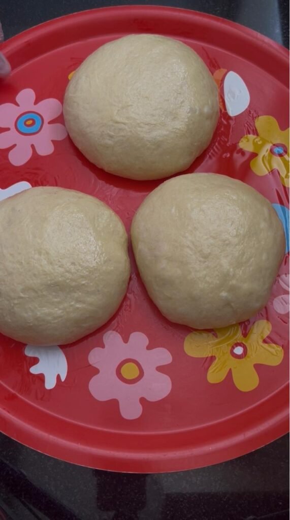 Risen dough divided into three equal-sized balls for homemade crescent rolls