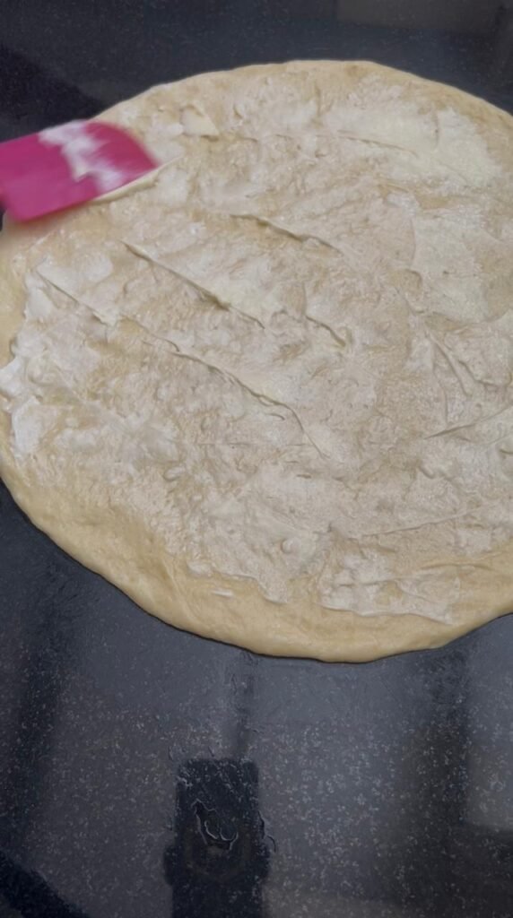 Dough ball pressed into thin circle with butter spread on top for homemade crescent rolls