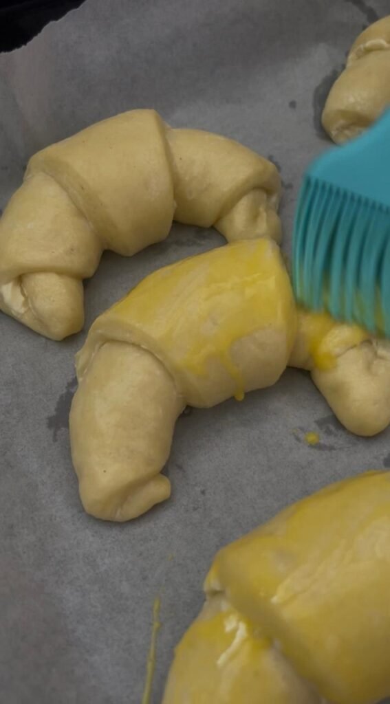 Egg yolk and milk mixture brushed onto homemade crescent rolls before baking
