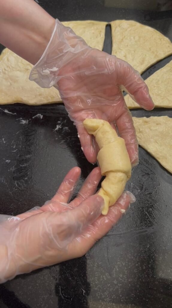 Croissant shapes formed by rolling triangles from base to point for homemade crescent rolls