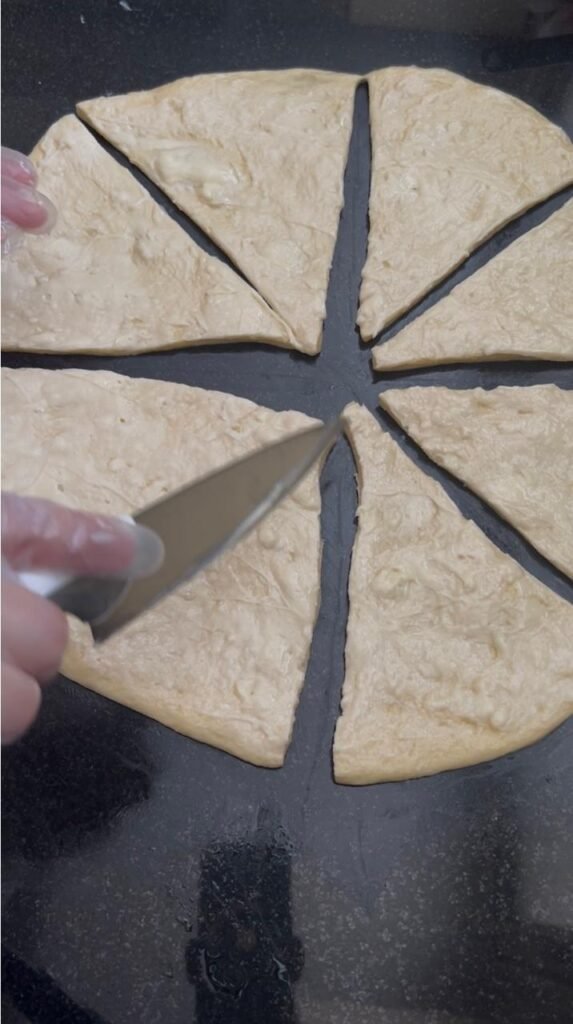 Dough circle sliced into 8 equal triangles for homemade crescent rolls, ready to roll