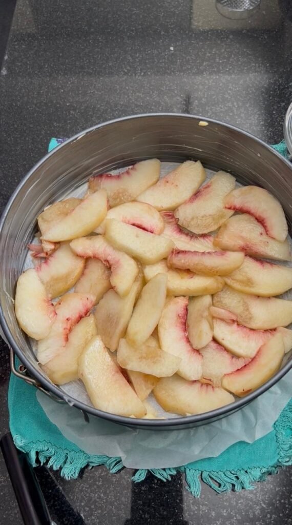 Sliced fresh peaches arranged in springform pan for easy peach cake