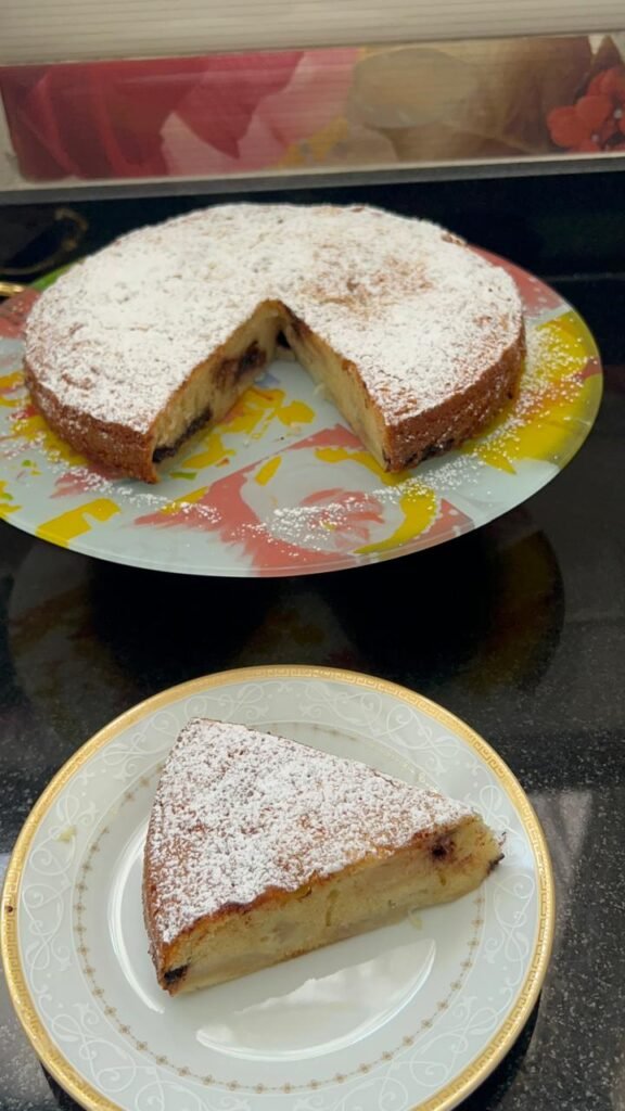 Whole easy peach cake in springform pan with peaches and chocolate visible